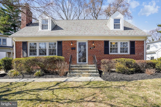 cape cod-style house featuring a front yard, brick siding, and a chimney