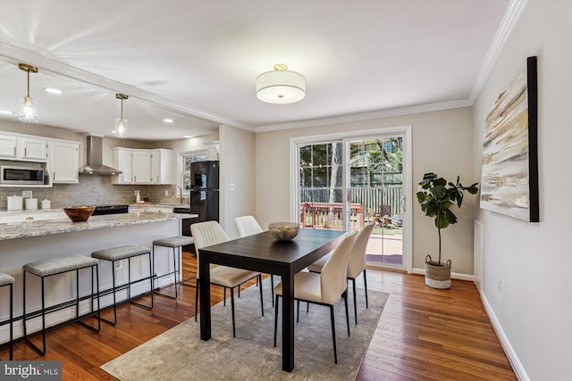 dining area with a baseboard radiator, baseboards, dark wood-type flooring, and crown molding