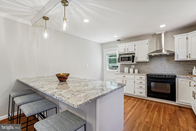 kitchen with black electric range, stainless steel microwave, a kitchen breakfast bar, wall chimney exhaust hood, and backsplash