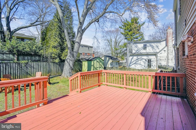 deck featuring a shed, a lawn, an outdoor structure, and fence