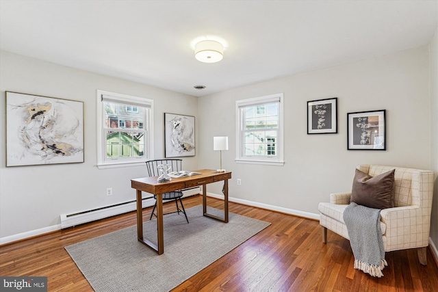 home office with a baseboard heating unit, wood-type flooring, and baseboards