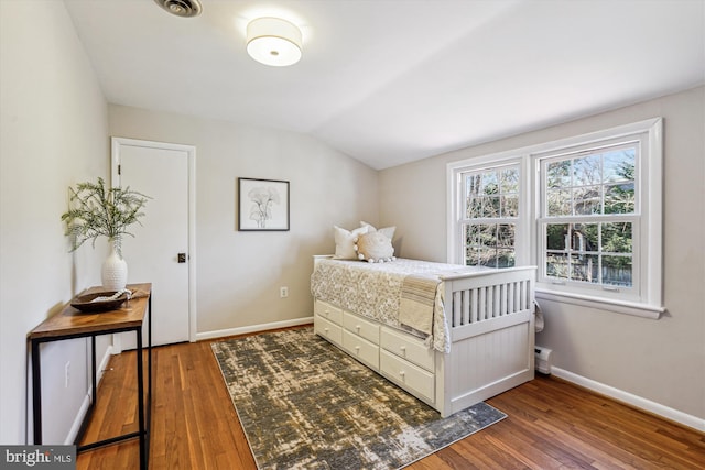 bedroom featuring visible vents, baseboards, lofted ceiling, and wood finished floors