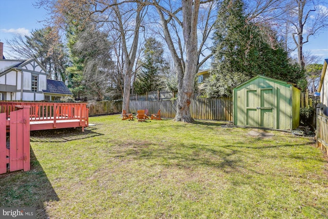 view of yard featuring an outbuilding, a wooden deck, a storage unit, and a fenced backyard