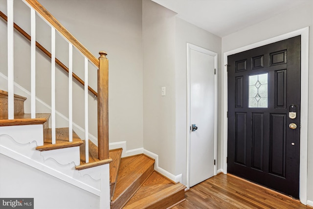 foyer with baseboards, wood finished floors, and stairs