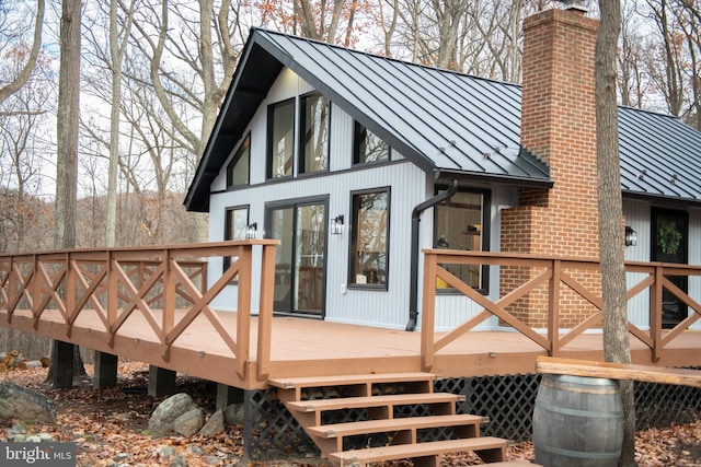 back of property with metal roof, a standing seam roof, and a chimney