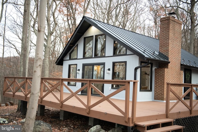 back of house with a deck, metal roof, brick siding, a standing seam roof, and a chimney