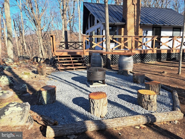 rear view of house with a deck, metal roof, stairway, a standing seam roof, and a chimney