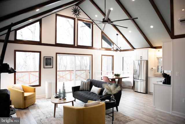 living room featuring ceiling fan with notable chandelier, high vaulted ceiling, beamed ceiling, and light wood-style floors