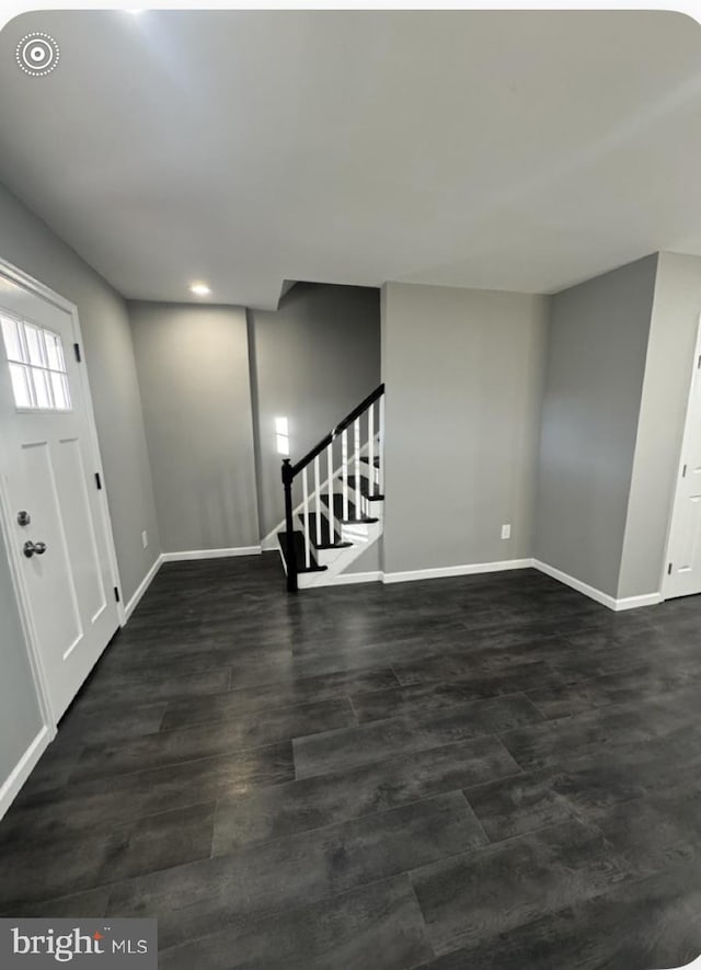 foyer entrance featuring dark wood-style flooring, stairway, and baseboards