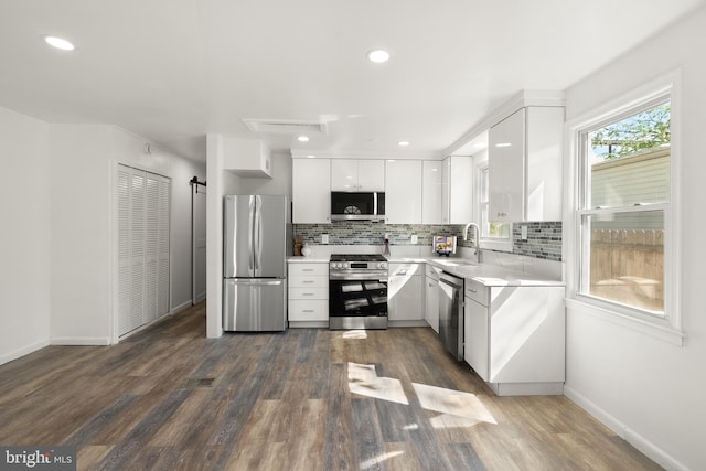 kitchen with light countertops, backsplash, white cabinets, and stainless steel appliances