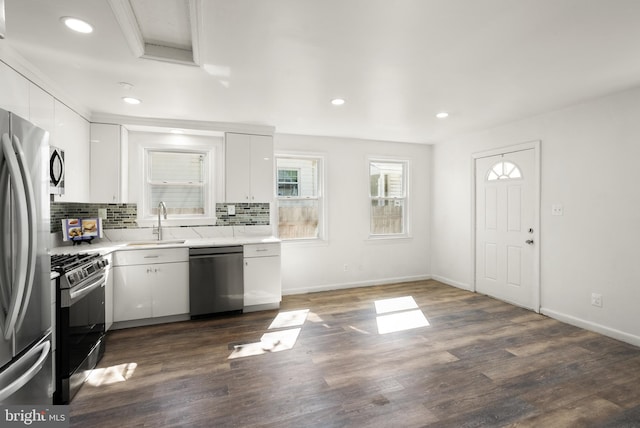 kitchen with decorative backsplash, stainless steel appliances, white cabinetry, and a sink
