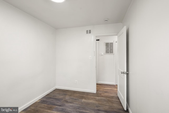 empty room featuring visible vents, baseboards, and dark wood-type flooring