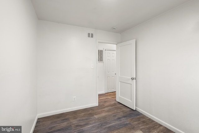 unfurnished bedroom featuring baseboards, dark wood-style flooring, and visible vents