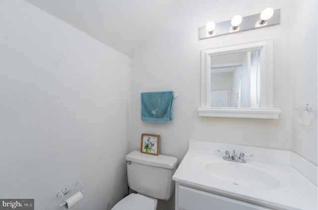 half bathroom with vaulted ceiling, vanity, and toilet