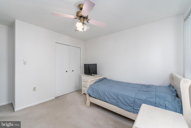 bedroom featuring ceiling fan, a closet, baseboards, and light colored carpet