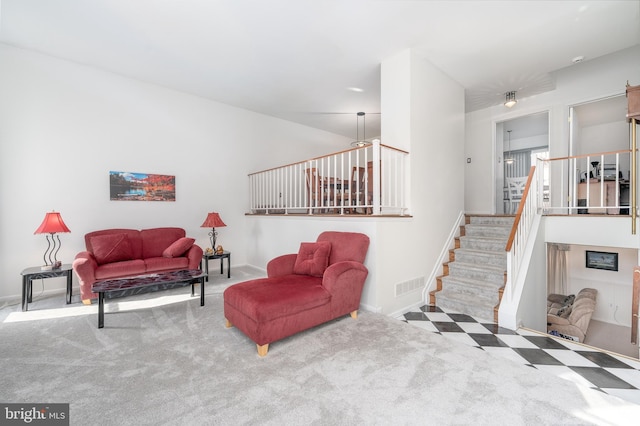 carpeted living area featuring visible vents, baseboards, and stairs