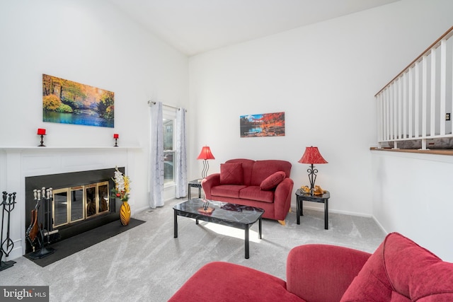 living area with carpet floors, a fireplace with flush hearth, and baseboards