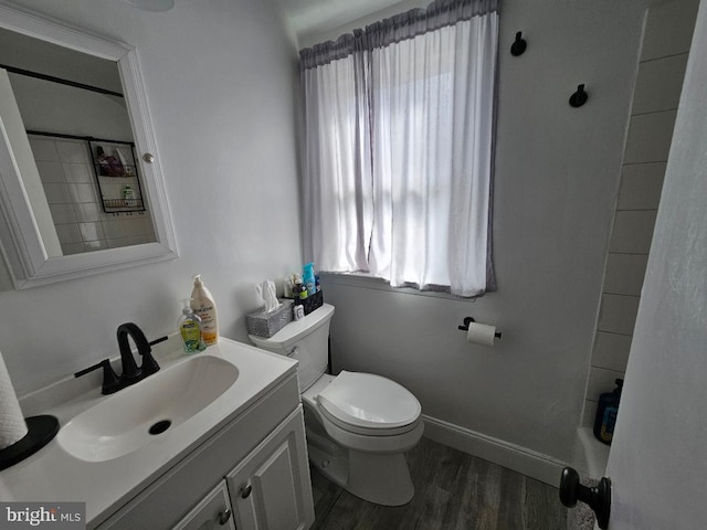 bathroom with toilet, baseboards, wood finished floors, and vanity