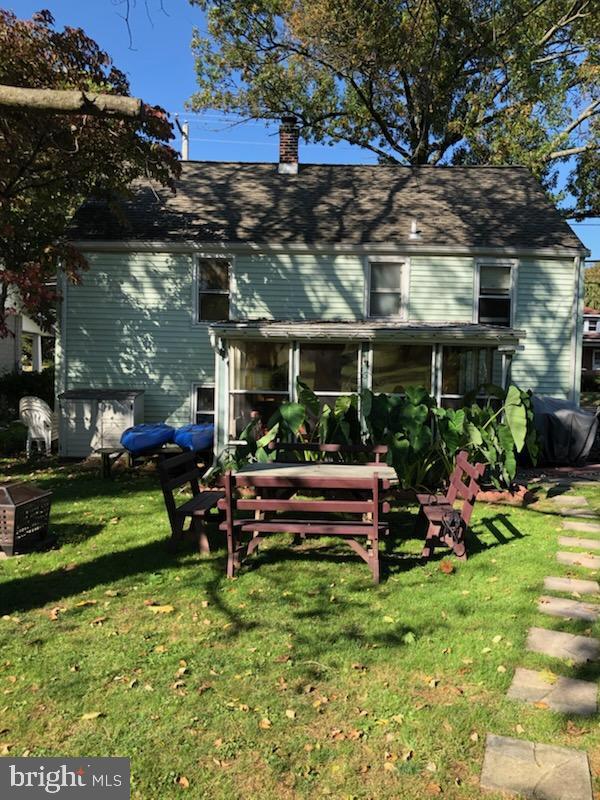 back of property with a chimney and a lawn