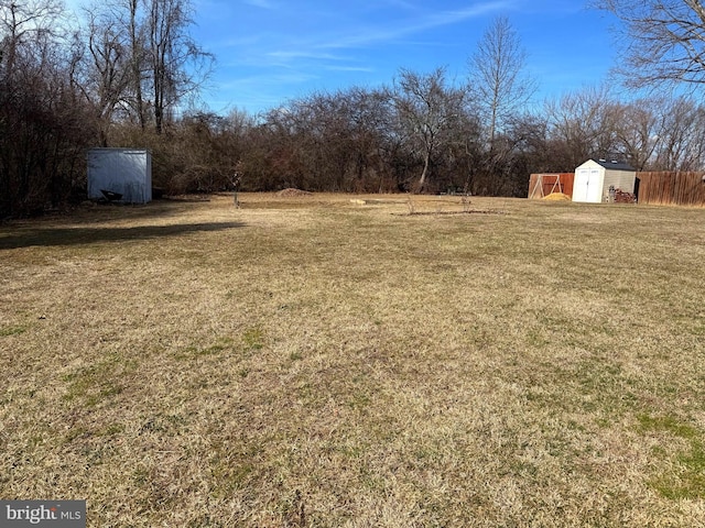 view of yard with an outbuilding, fence, and a shed