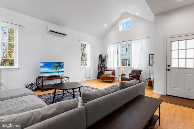 living room featuring light wood finished floors, baseboards, high vaulted ceiling, and an AC wall unit