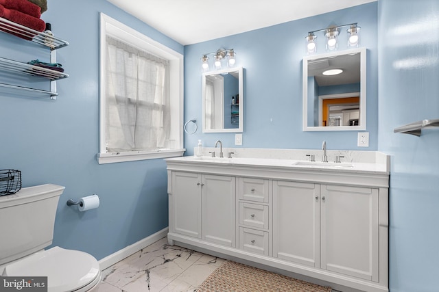 bathroom with toilet, marble finish floor, baseboards, and a sink