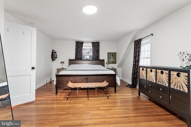 bedroom featuring light wood-type flooring, visible vents, and baseboards