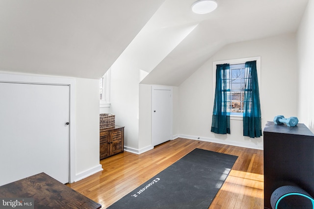 interior space with vaulted ceiling, hardwood / wood-style floors, and baseboards