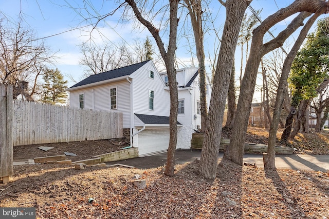 view of home's exterior with a garage and fence