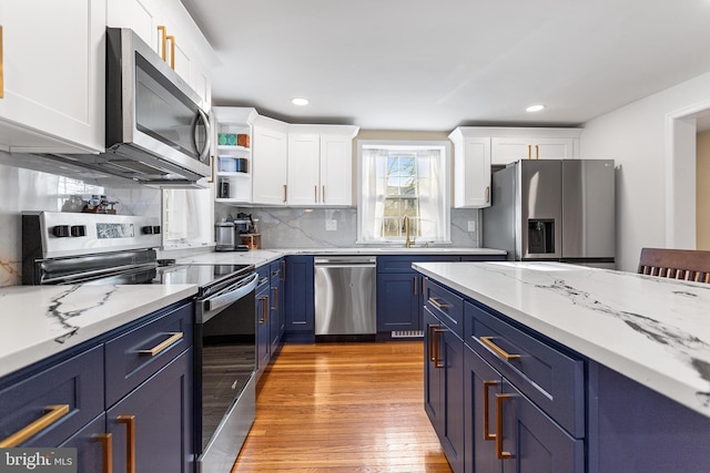 kitchen with blue cabinets, light wood-style floors, white cabinetry, and stainless steel appliances