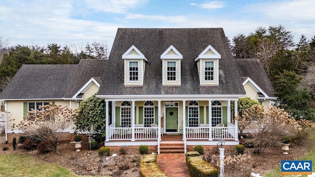 new england style home with covered porch and a shingled roof