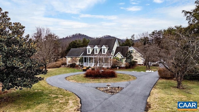 cape cod house with aphalt driveway, covered porch, and a front yard