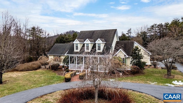 new england style home with a front yard and covered porch