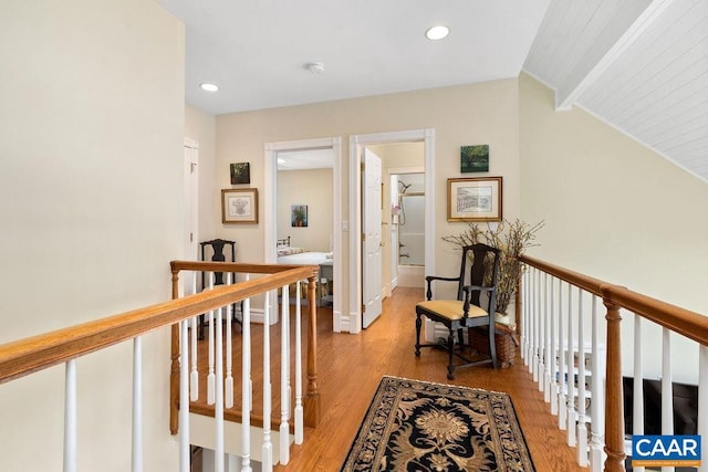 hall featuring lofted ceiling with beams, light wood-type flooring, an upstairs landing, and recessed lighting