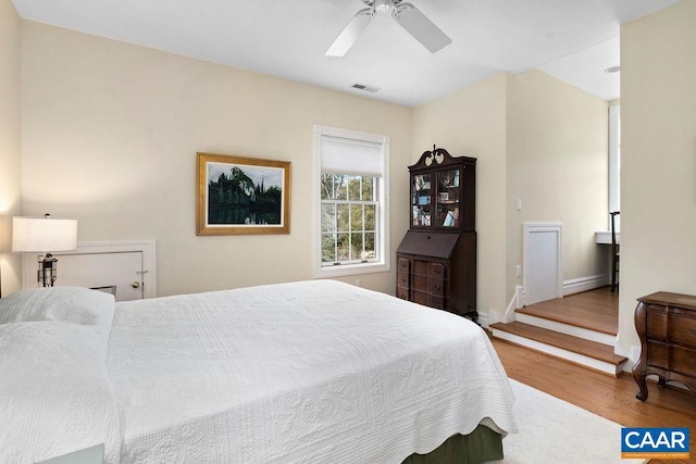 bedroom featuring visible vents, baseboards, ceiling fan, and wood finished floors