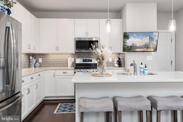 kitchen with stainless steel appliances, dark wood finished floors, a sink, and a kitchen bar