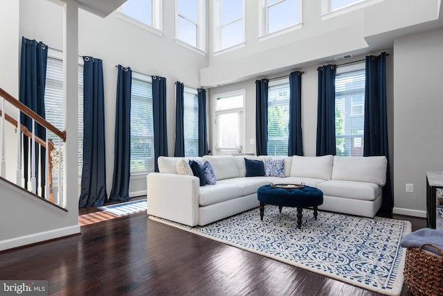 living area with visible vents, a high ceiling, baseboards, and wood finished floors