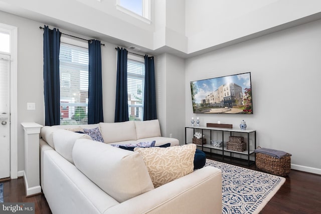 living room with a high ceiling, baseboards, and dark wood-type flooring