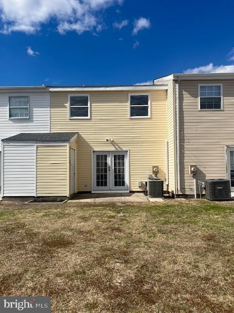 back of property with an outbuilding, french doors, central AC, and a yard