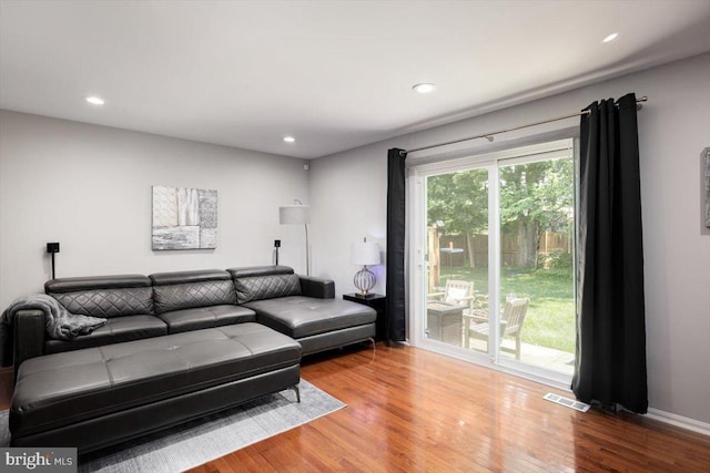 living room with baseboards, wood finished floors, visible vents, and recessed lighting