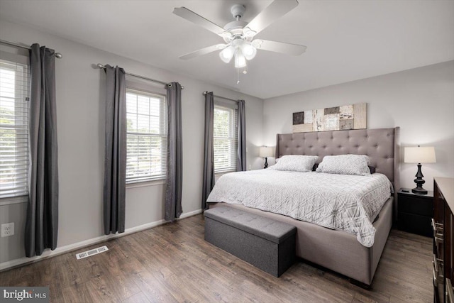 bedroom with a ceiling fan, baseboards, visible vents, and wood finished floors