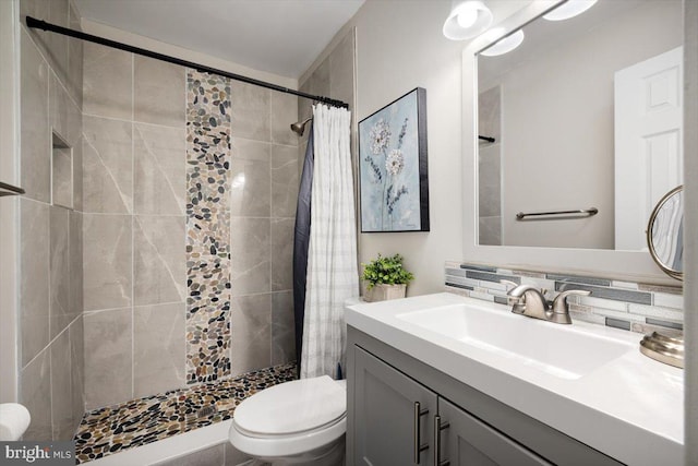 bathroom featuring toilet, tasteful backsplash, tiled shower, and vanity