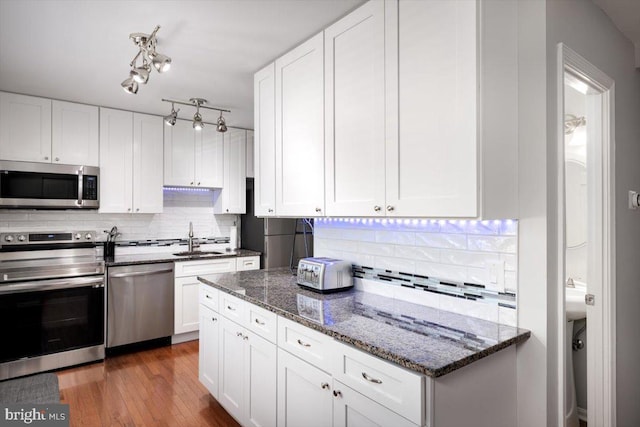 kitchen with white cabinetry, appliances with stainless steel finishes, a sink, and wood finished floors