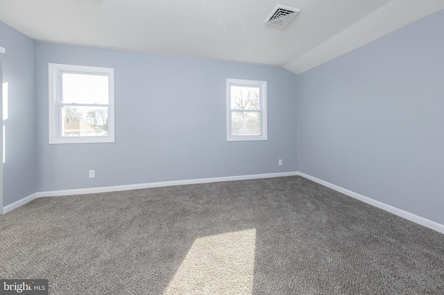 carpeted empty room featuring visible vents, vaulted ceiling, and baseboards