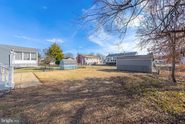 view of yard with a fenced backyard, a storage unit, and an outbuilding