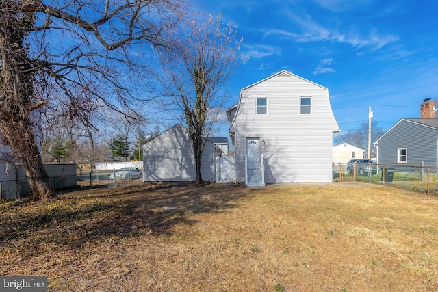 rear view of property with a yard, a gambrel roof, and fence