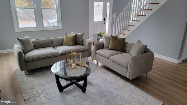 living area with baseboards, plenty of natural light, stairway, and wood finished floors