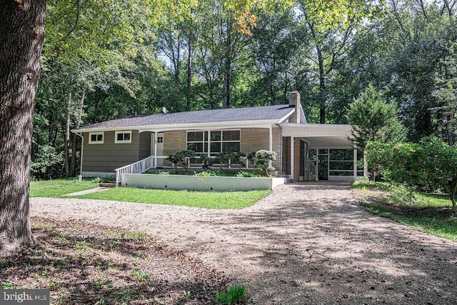 single story home featuring dirt driveway, an attached carport, and a chimney