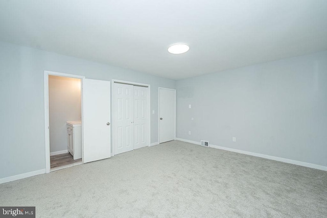 unfurnished bedroom with ensuite bathroom, carpet floors, visible vents, and baseboards