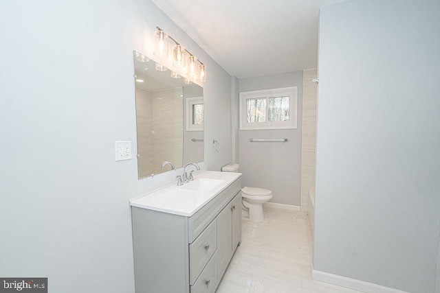 bathroom featuring toilet, walk in shower, vanity, and baseboards